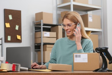 Photo of Seller talking on phone while working in office. Online store