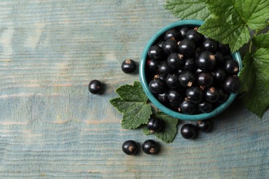 Ripe blackcurrants and leaves on wooden rustic table, flat lay. Space for text