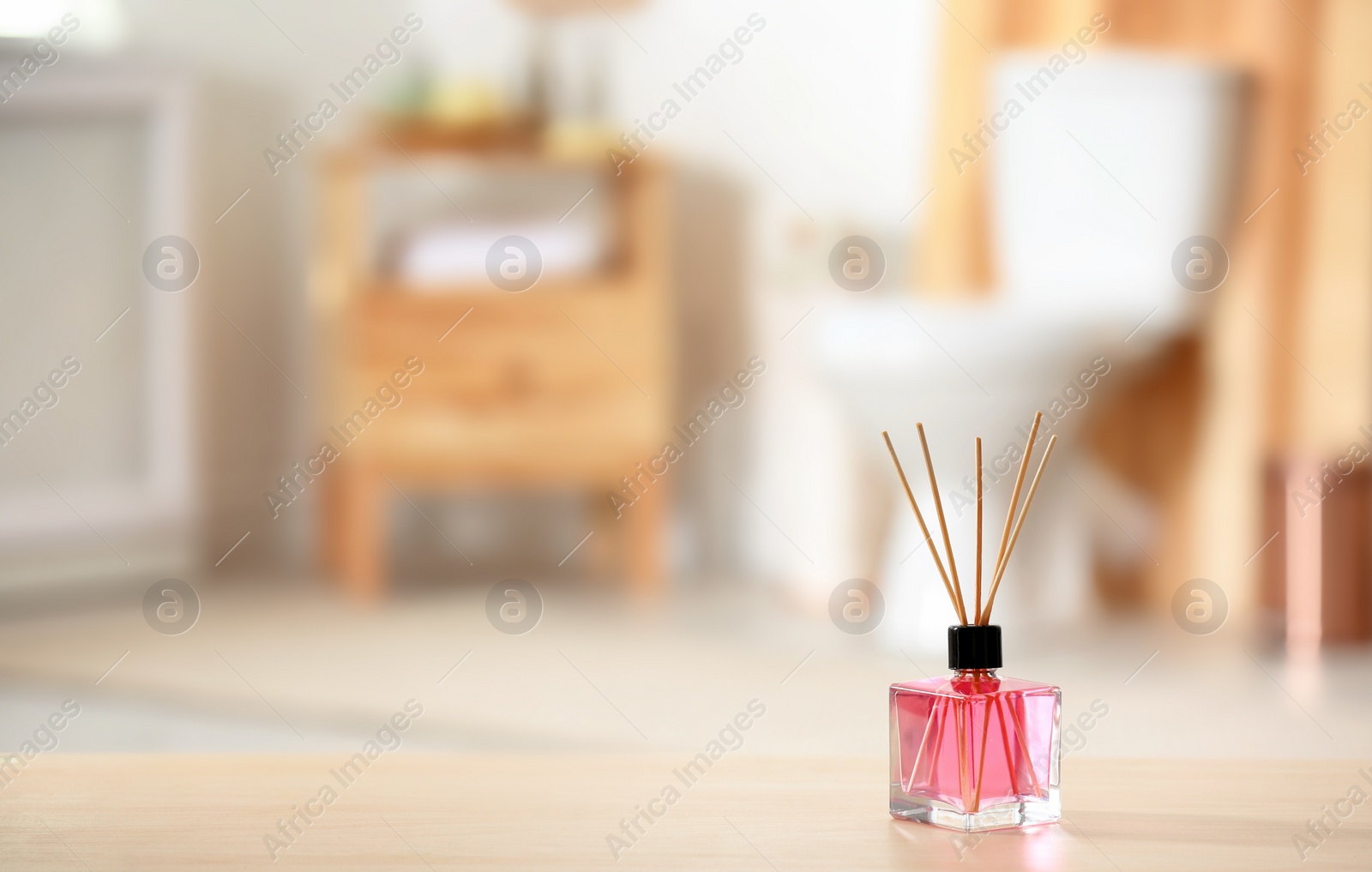 Photo of Aromatic reed air freshener on table against blurred background