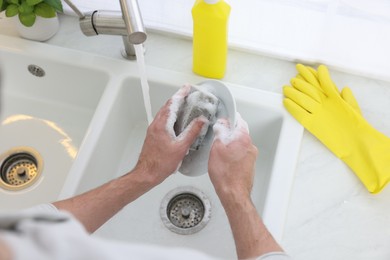 Photo of Man washing plate in kitchen sink, above view