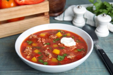 Photo of Bowl of delicious stuffed pepper soup on light blue wooden table