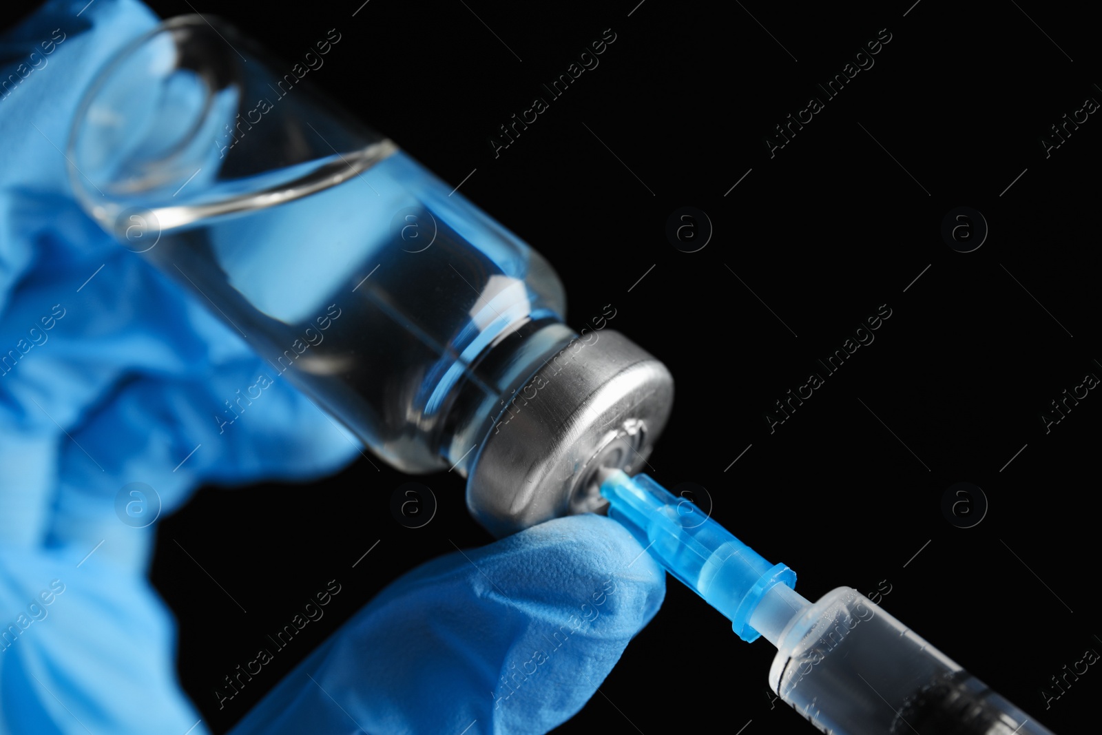 Photo of Doctor filling syringe with medication on black background, closeup. Vaccination and immunization