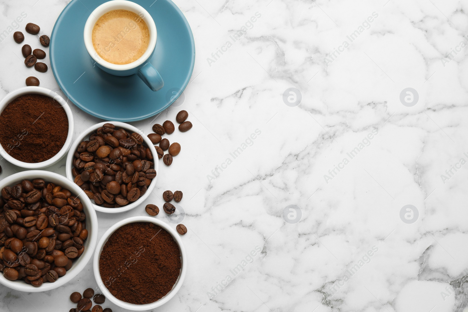 Photo of Coffee beans, powder and cup of drink on white marble table, flat lay. Space for text