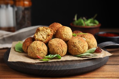 Photo of Delicious falafel balls with herbs on wooden table