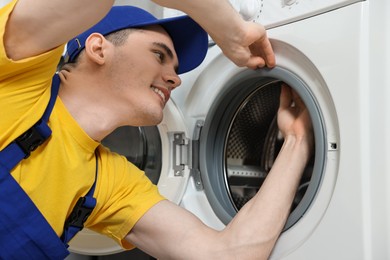 Photo of Smiling plumber checking door gasket of washing machine
