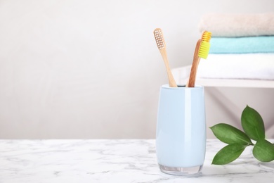 Bamboo toothbrushes on marble table against light background. Space for text