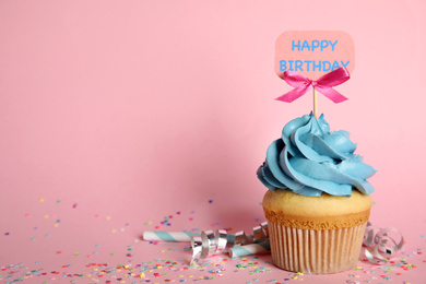 Photo of Beautiful birthday cupcake, streamers and confetti on pink background. Space for text