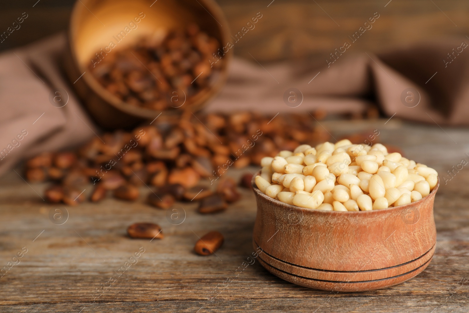 Photo of Bowl with pine nuts on wooden table. Space for text