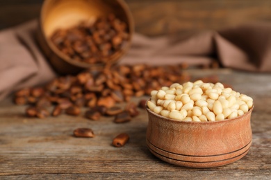 Bowl with pine nuts on wooden table. Space for text