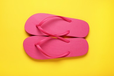 Photo of Stylish pink flip flops on yellow background, top view
