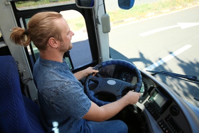 Photo of Professional bus driver at steering wheel. Passenger transportation