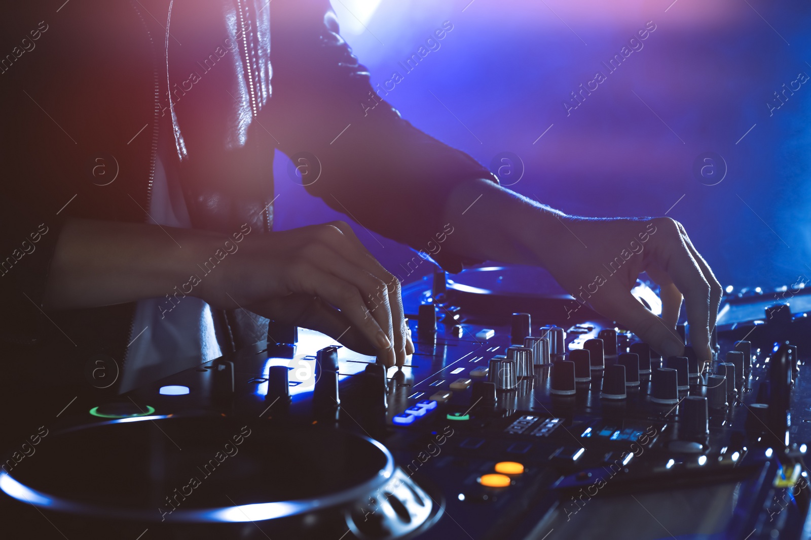 Photo of DJ creating music on modern console mixer in night club, closeup