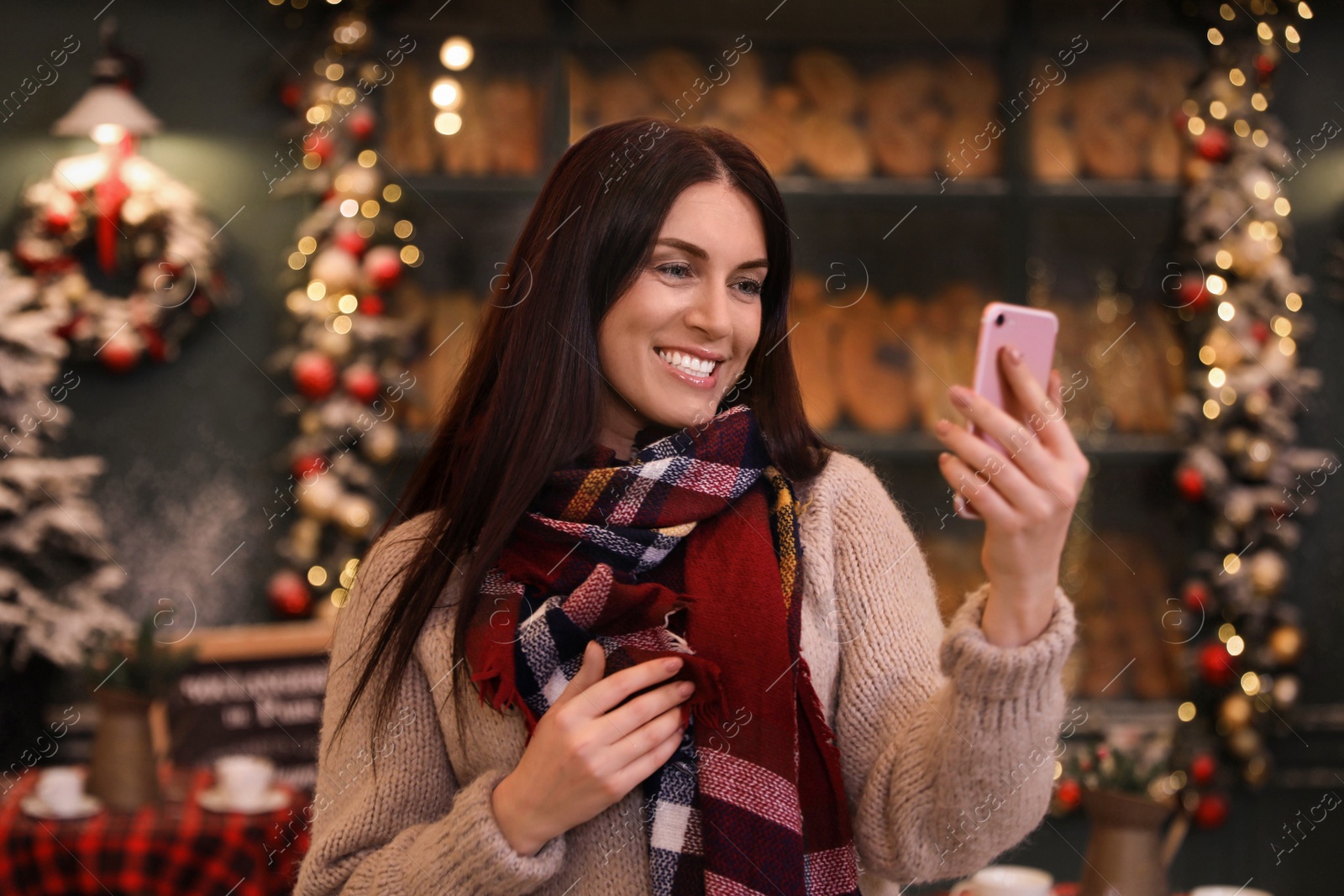 Photo of Beautiful woman using mobile phone in decorated cafe. Christmas celebration