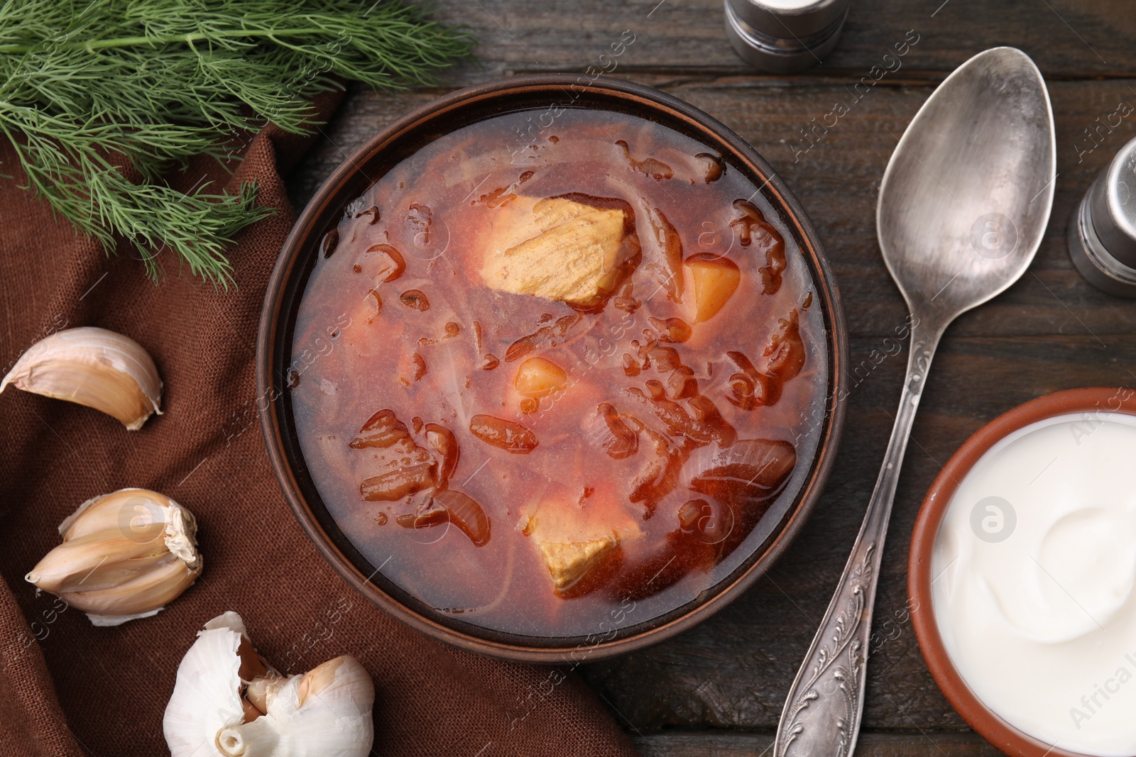 Photo of Delicious borscht, garlic and sour cream on wooden table, flat lay