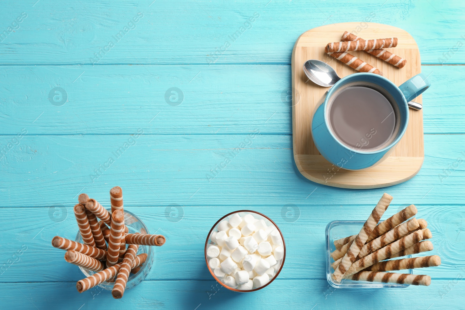 Photo of Chocolate wafer rolls, marshmallows and cup of cocoa on wooden background, top view with space for text