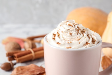 Cup with tasty pumpkin spice latte on white table, closeup