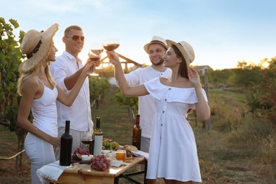 Photo of Friends clinking glasses of red wine in vineyard