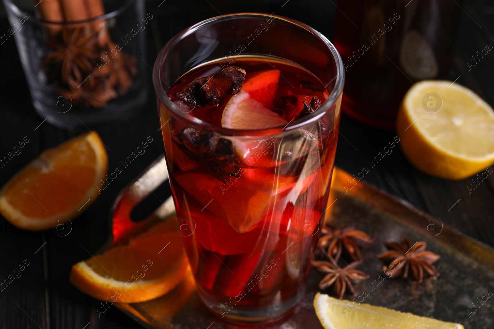 Photo of Glass of aromatic punch drink and ingredients on table, closeup