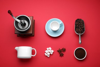 Flat lay composition with vintage manual coffee grinder and beans on red background