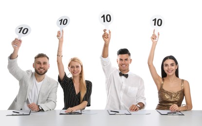 Photo of Panel of judges holding signs with highest score at table on white background