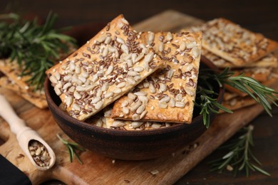 Photo of Cereal crackers with flax, sunflower, sesame seeds and rosemary on table, closeup
