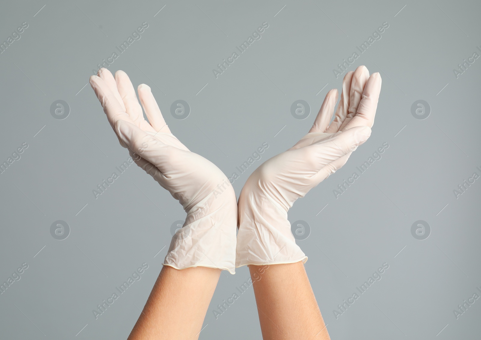 Photo of Doctor wearing medical gloves on grey background, closeup