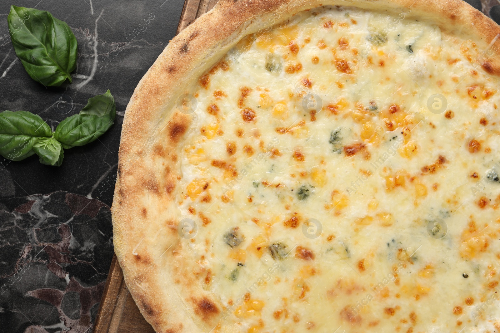 Photo of Delicious cheese pizza and basil on black marble table, flat lay