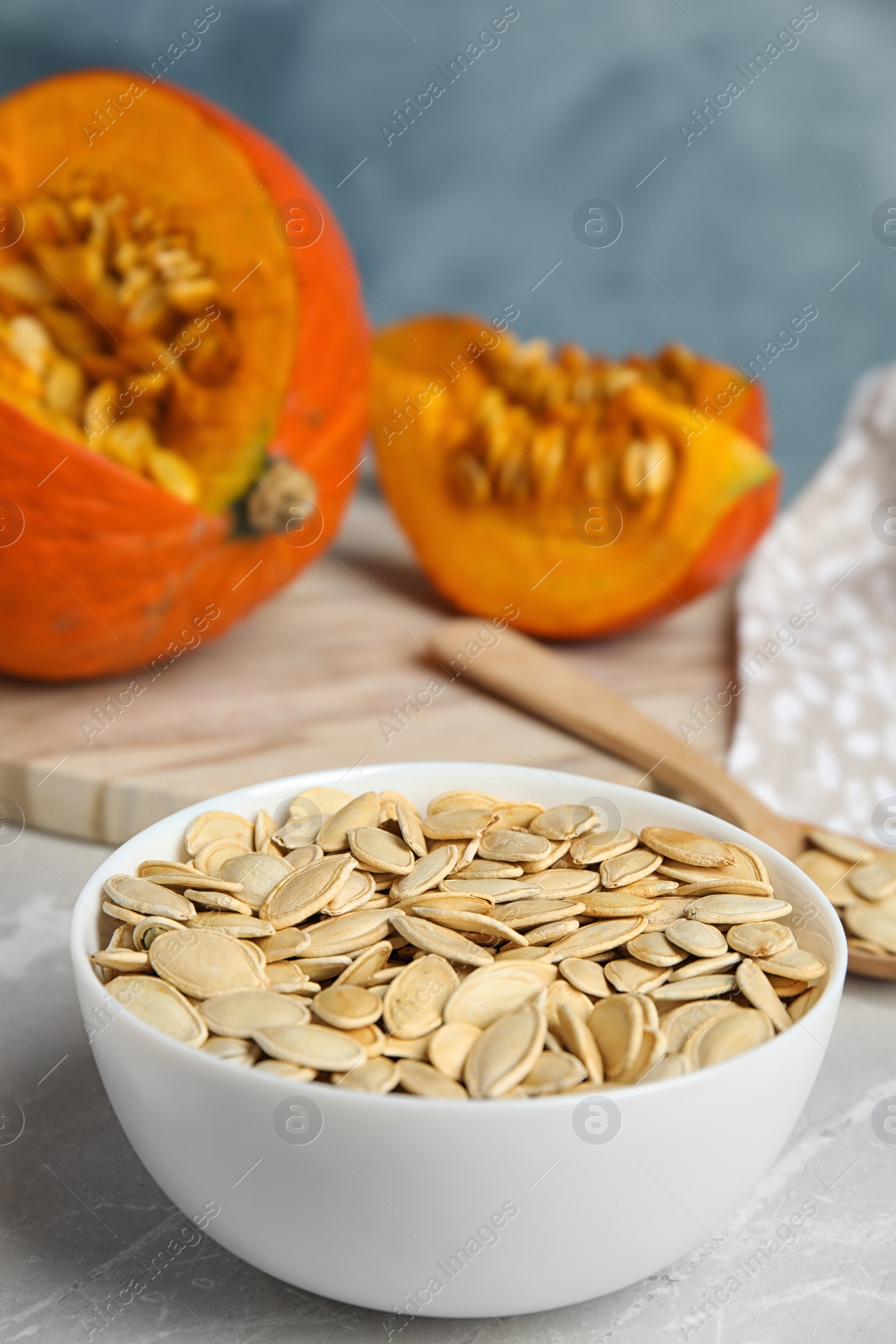 Photo of Bowl of raw pumpkin seeds on light grey marble table. Space for text