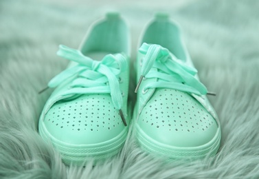Photo of Stylish mint sneakers on fuzzy rug, closeup