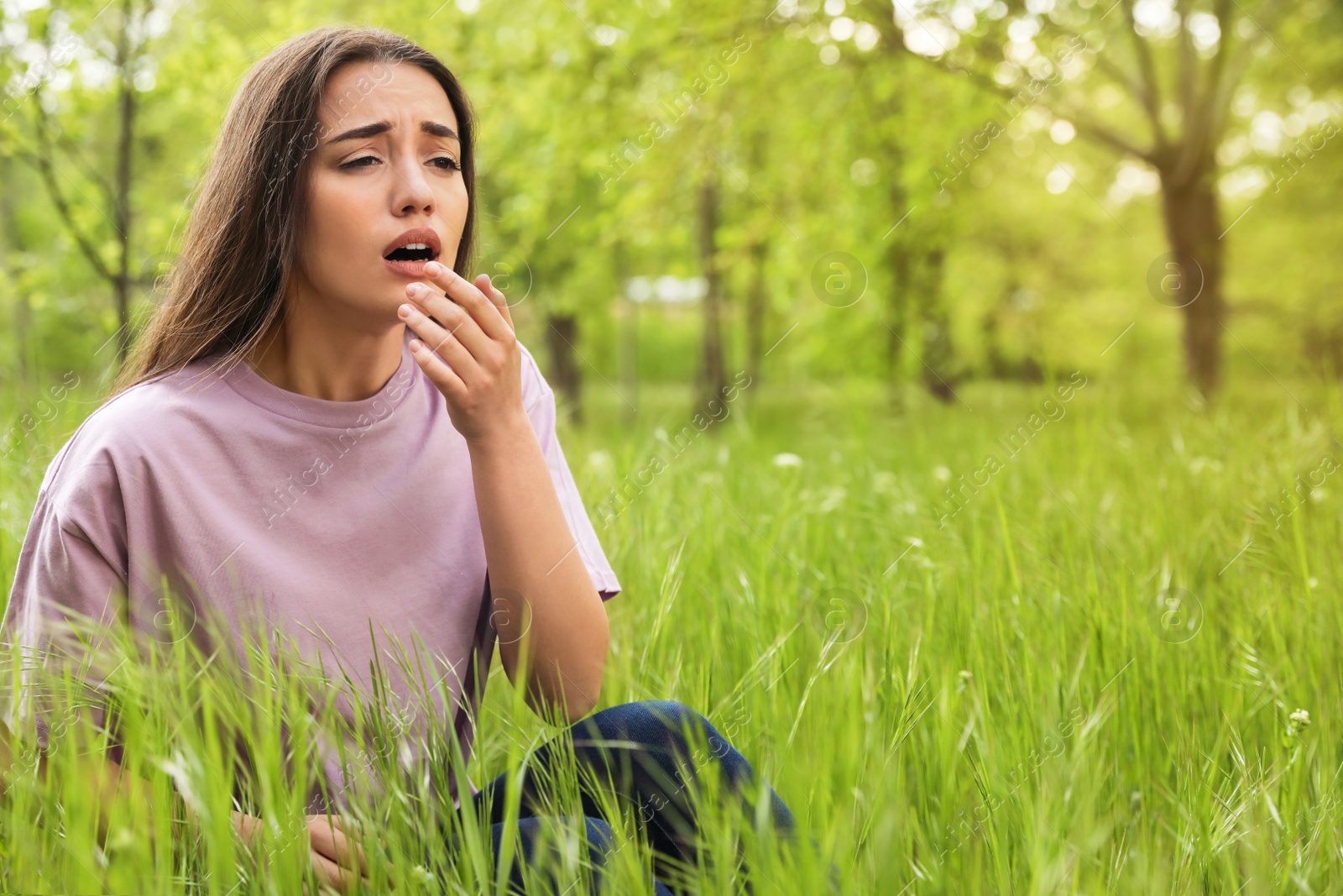 Photo of Young woman suffering from seasonal allergy outdoors, space for text