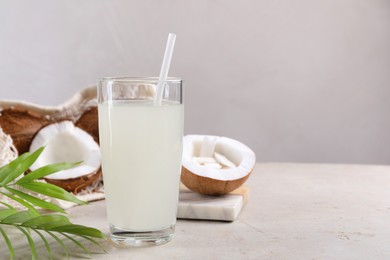 Glass of coconut water, palm leaves and nuts on light table. Space for text