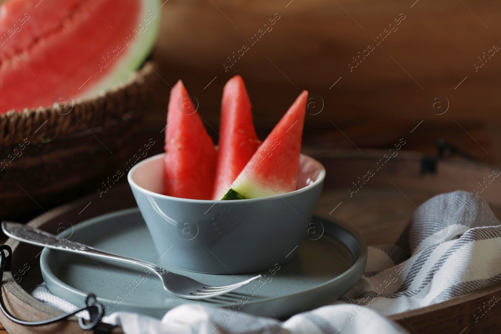 Photo of Fresh juicy watermelon in bowl on wooden tray, closeup