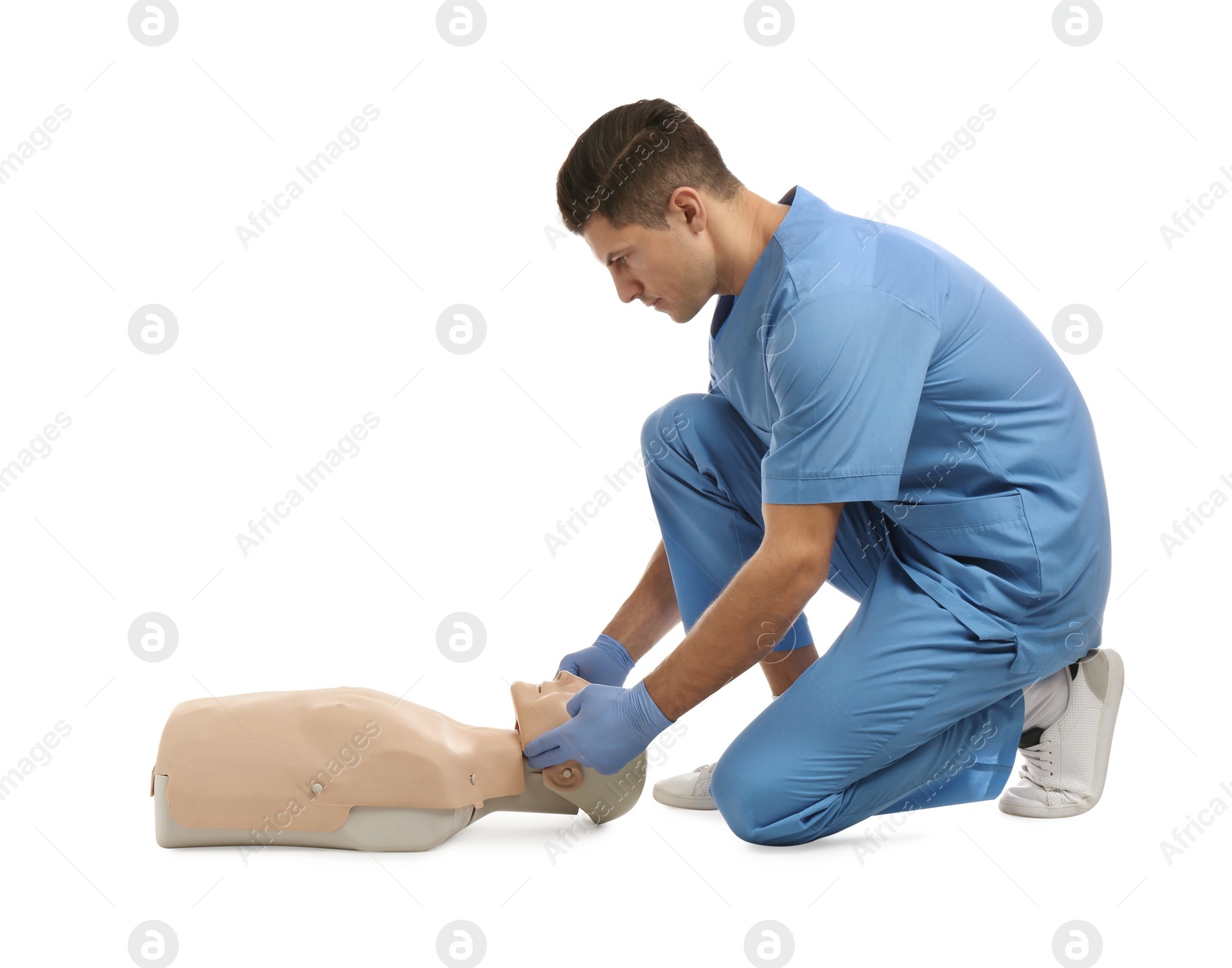 Photo of Doctor in uniform practicing first aid on mannequin against white background