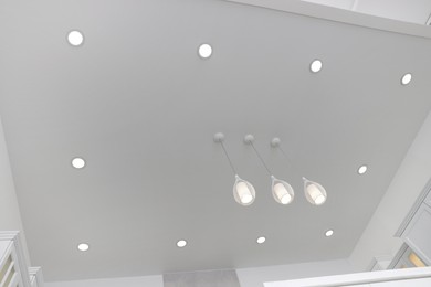 Photo of Ceiling with modern lamps in stylish room, low angle view