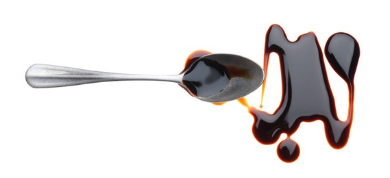 Spilled soy sauce and spoon on white background, top view