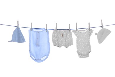 Photo of Different baby clothes drying on laundry line against white background