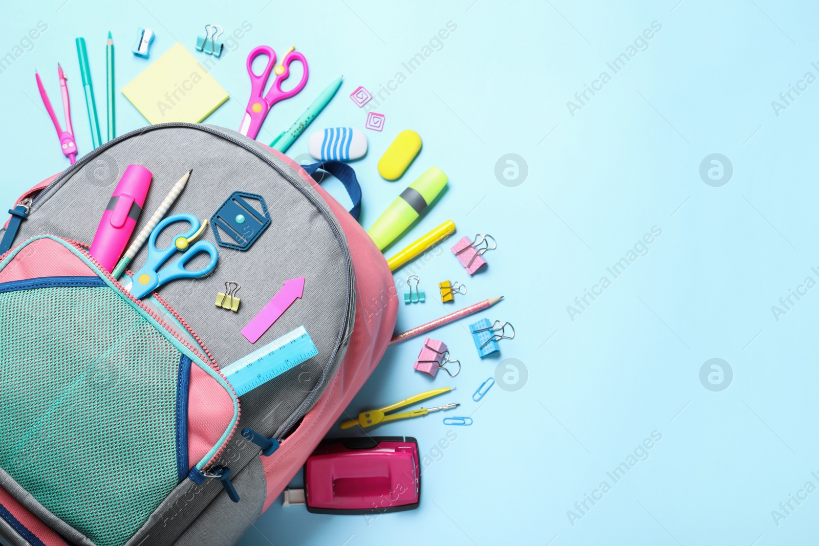 Photo of Stylish backpack with different school stationery on light blue background, flat lay. Space for text