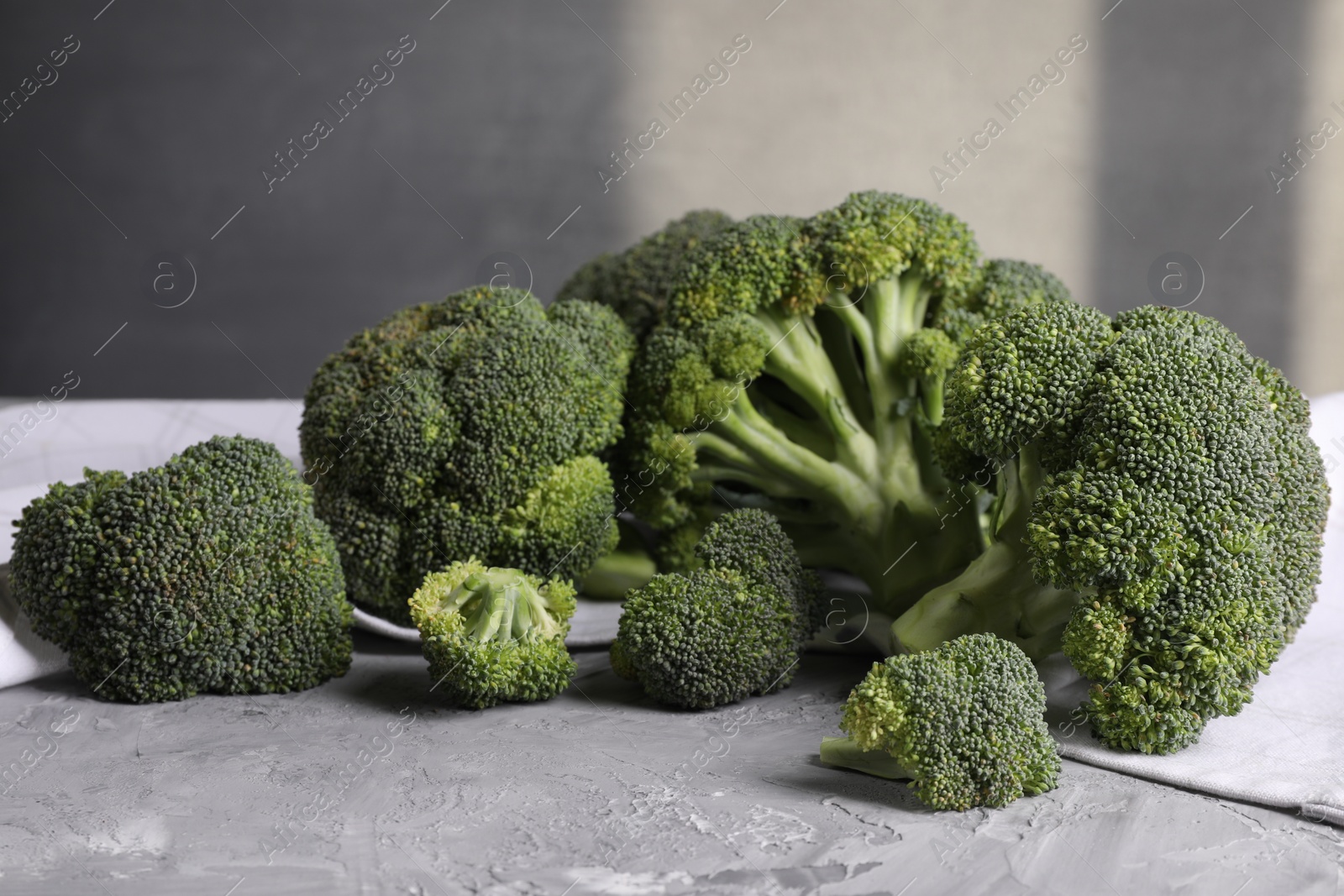 Photo of Fresh raw broccoli on grey textured table, closeup