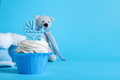 Photo of Beautifully decorated baby shower cupcake with cream and boy topper on light blue background. Space for text