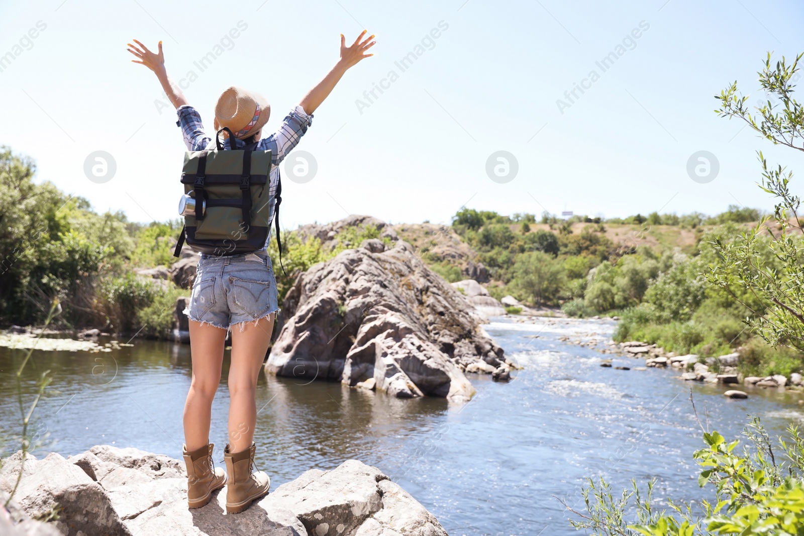 Photo of Young woman on rock near river. Summer camp