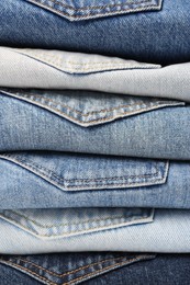 Stack of different folded jeans as background, closeup
