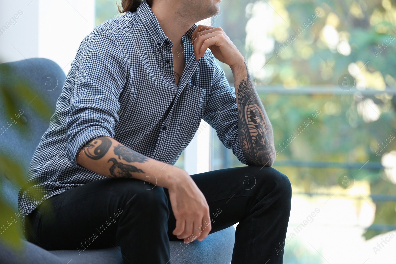 Photo of Young man with stylish tattoos at home