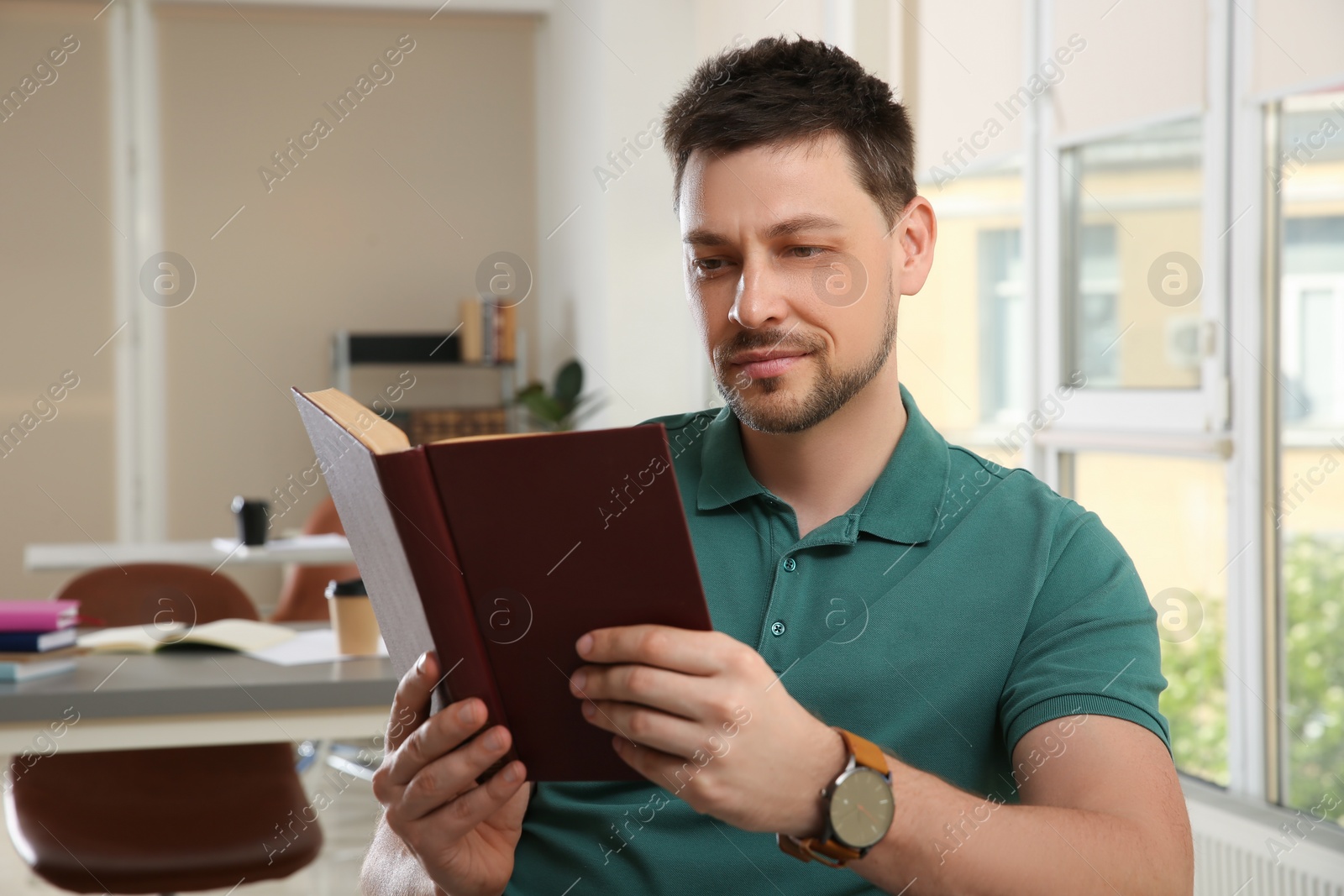 Photo of Handsome man reading book in university library