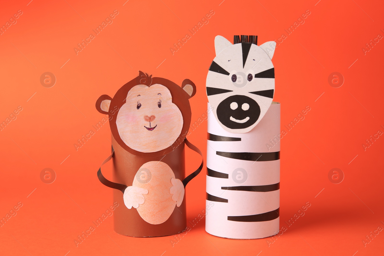 Photo of Toy monkey and zebra made from toilet paper hubs on orange background. Children's handmade ideas