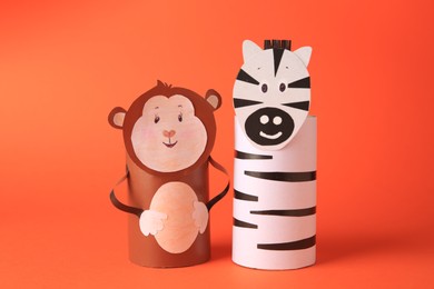 Photo of Toy monkey and zebra made from toilet paper hubs on orange background. Children's handmade ideas