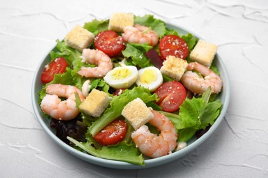 Photo of Delicious Caesar salad with shrimps on white textured table, closeup