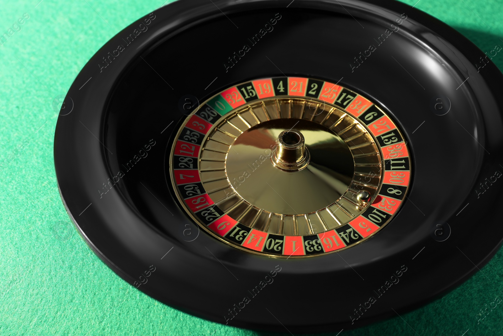 Photo of Roulette wheel with ball on green table, closeup. Casino game