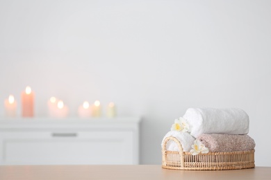 Photo of Tray with towels and flowers on table against blurred background, space for text. Spa concept