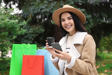 Photo of Special Promotion. Happy young woman with smartphone and cup of drink in park