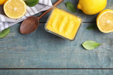 Delicious lemon curd in bowl on wooden table, flat lay. Space for text